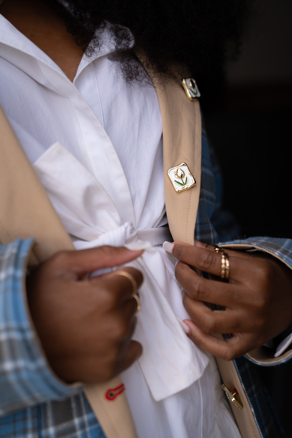 Person adjusting a white shirt with a beige jacket and plaid sleeves. womens barn jacket power woman
