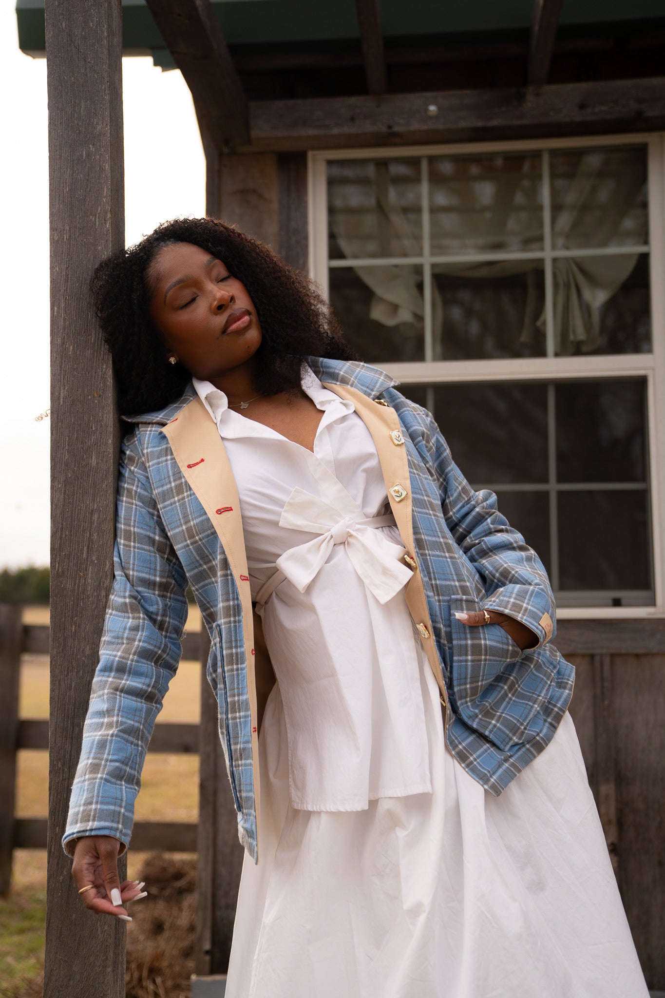 Woman in a white dress with a blue plaid jacket standing on a wooden porch. womens barn jacket power woman
