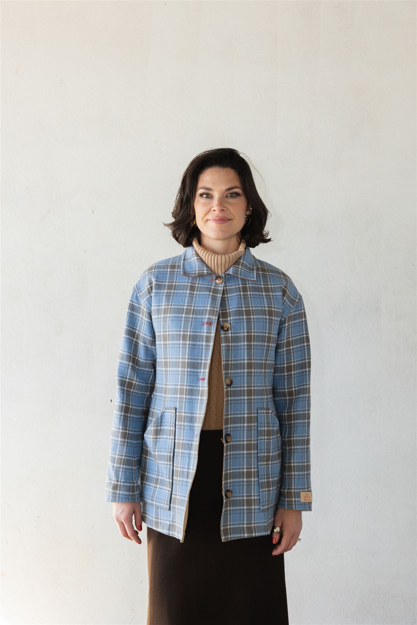 Woman wearing a blue plaid barn jacket against a white background power woman