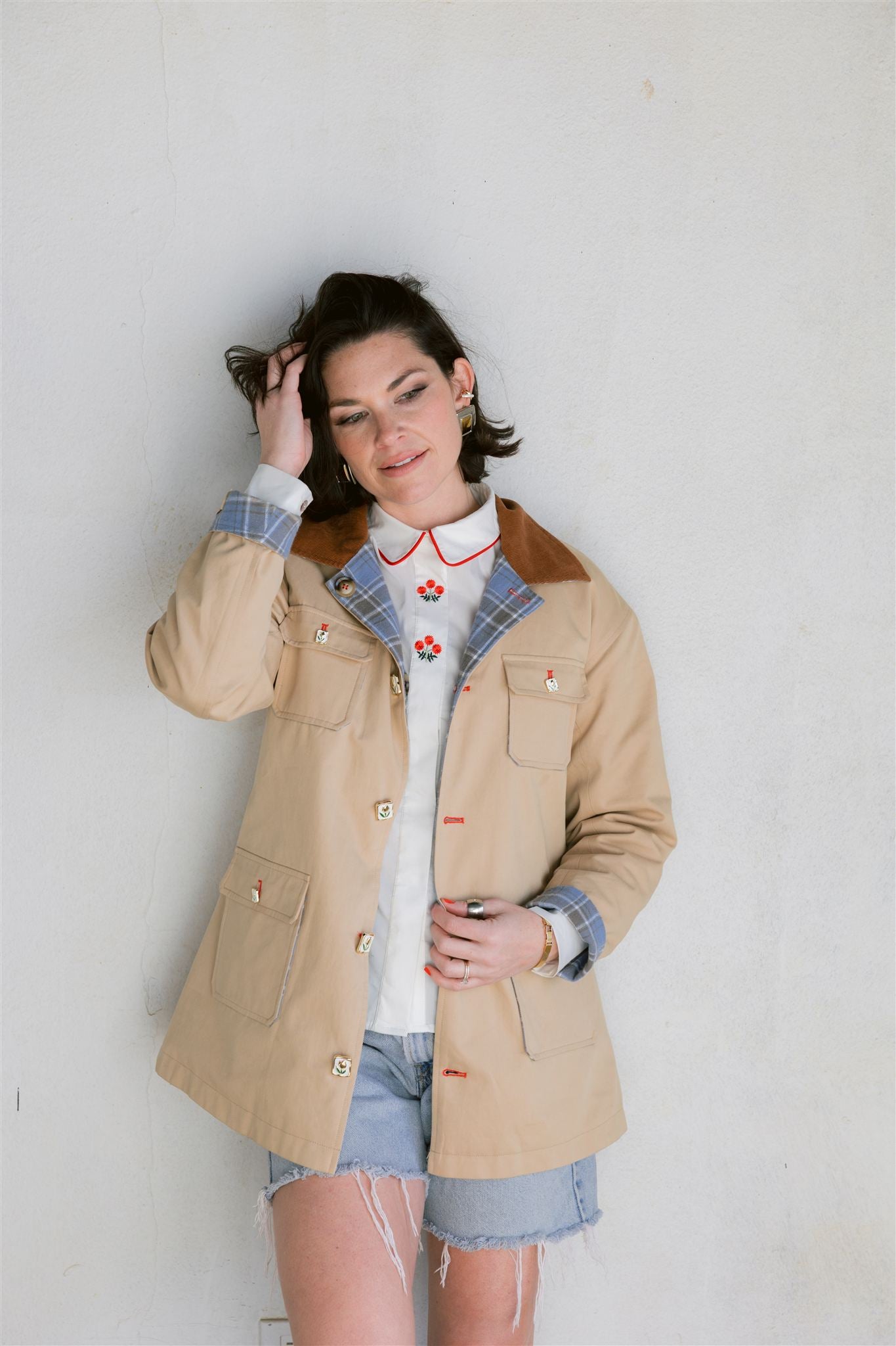 Person wearing a beige barn jacket with a white wall background