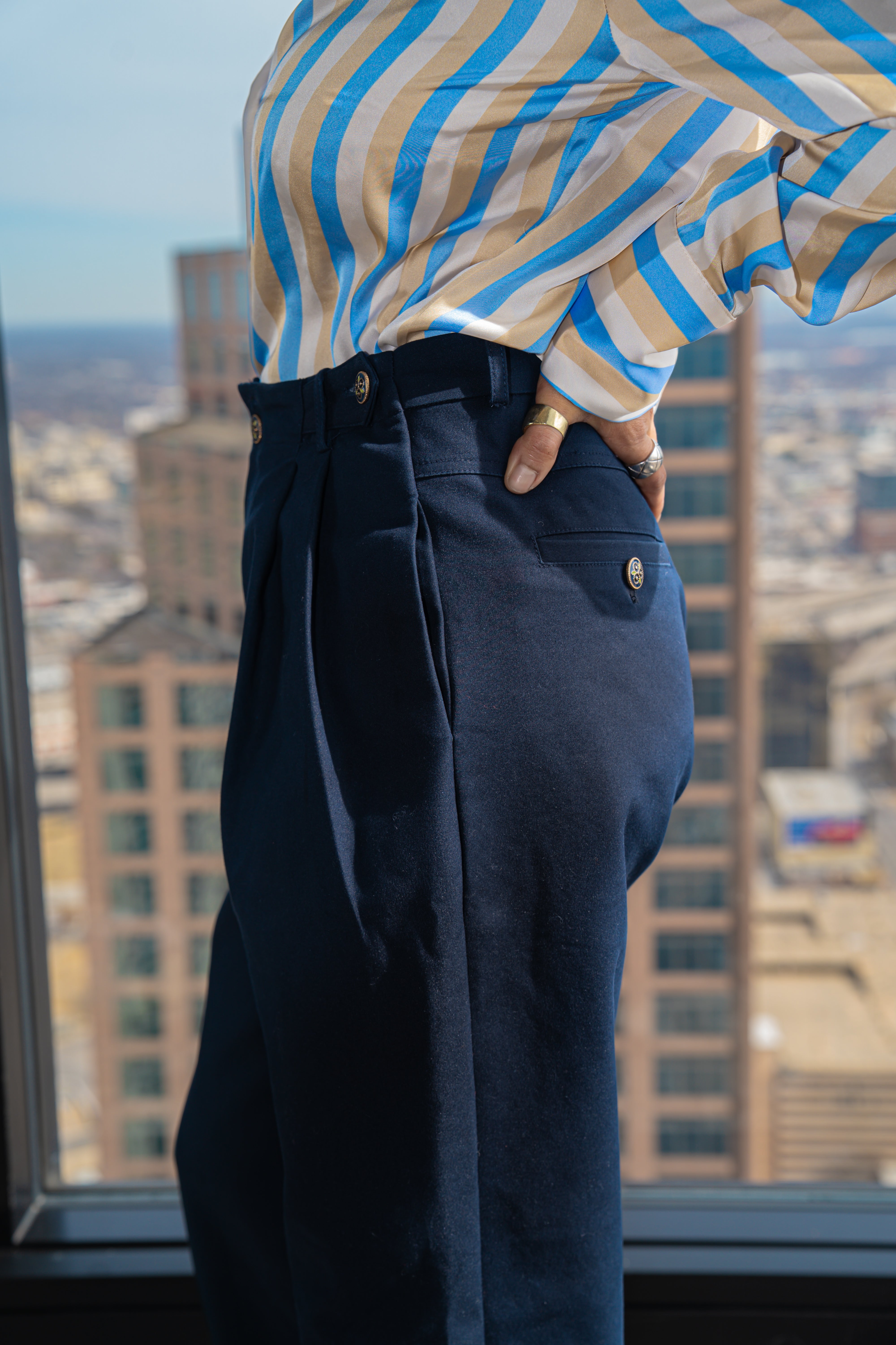 Person wearing a striped shirt and dark pants with a cityscape in the background womens trouser pwr wmn power woman 